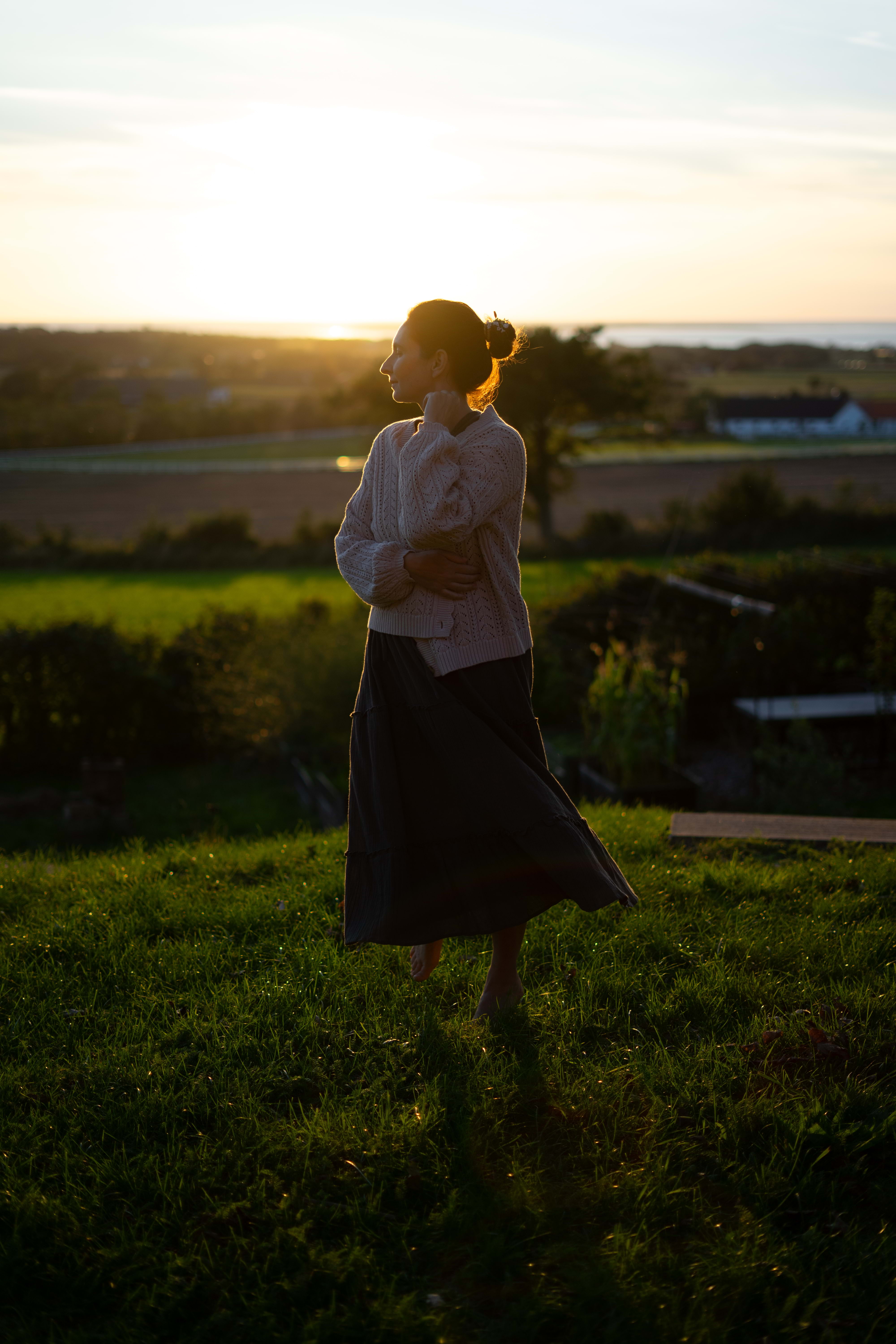 Woman standing in a meadow at sunset