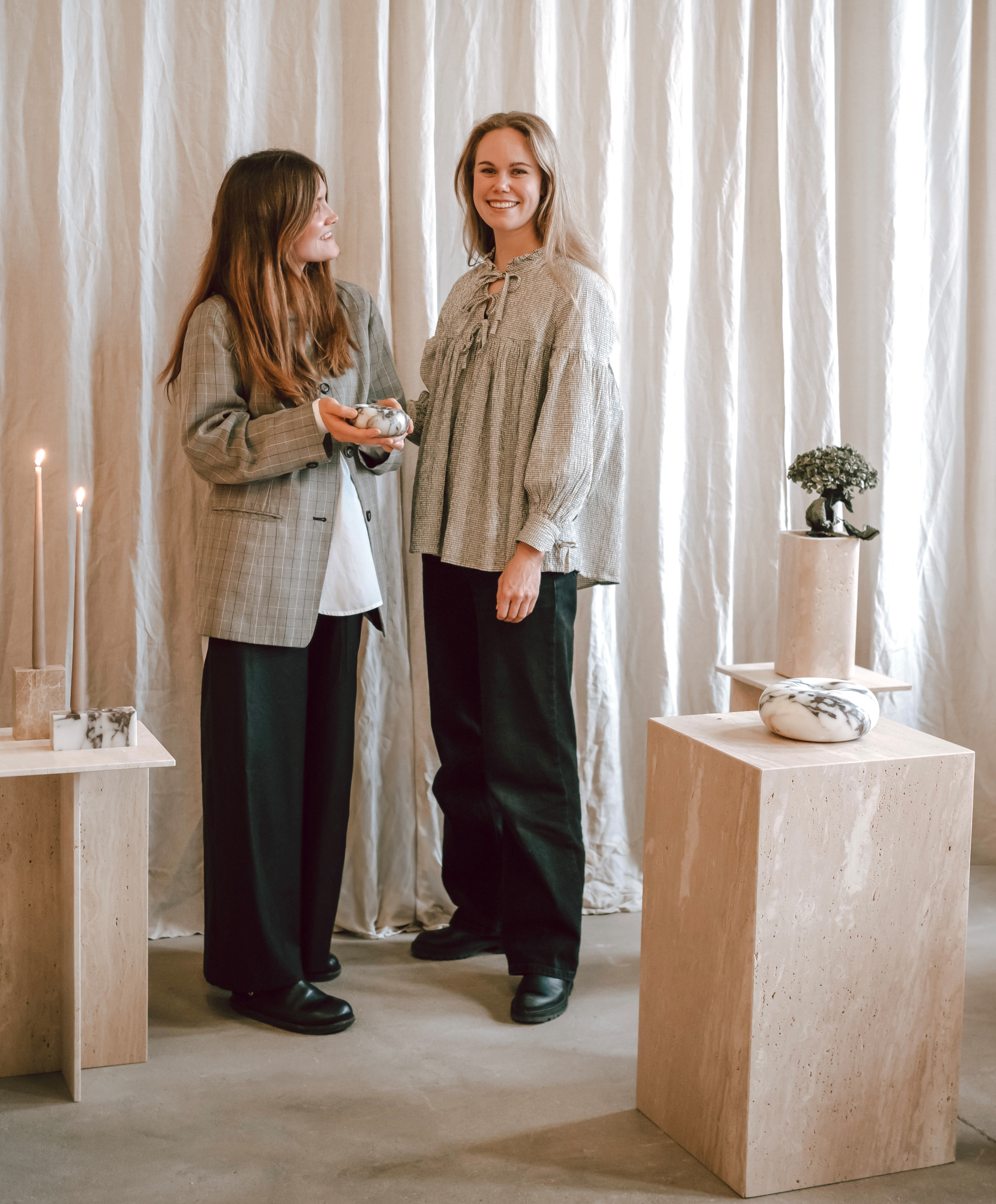 Two women standing in a softly lit studio