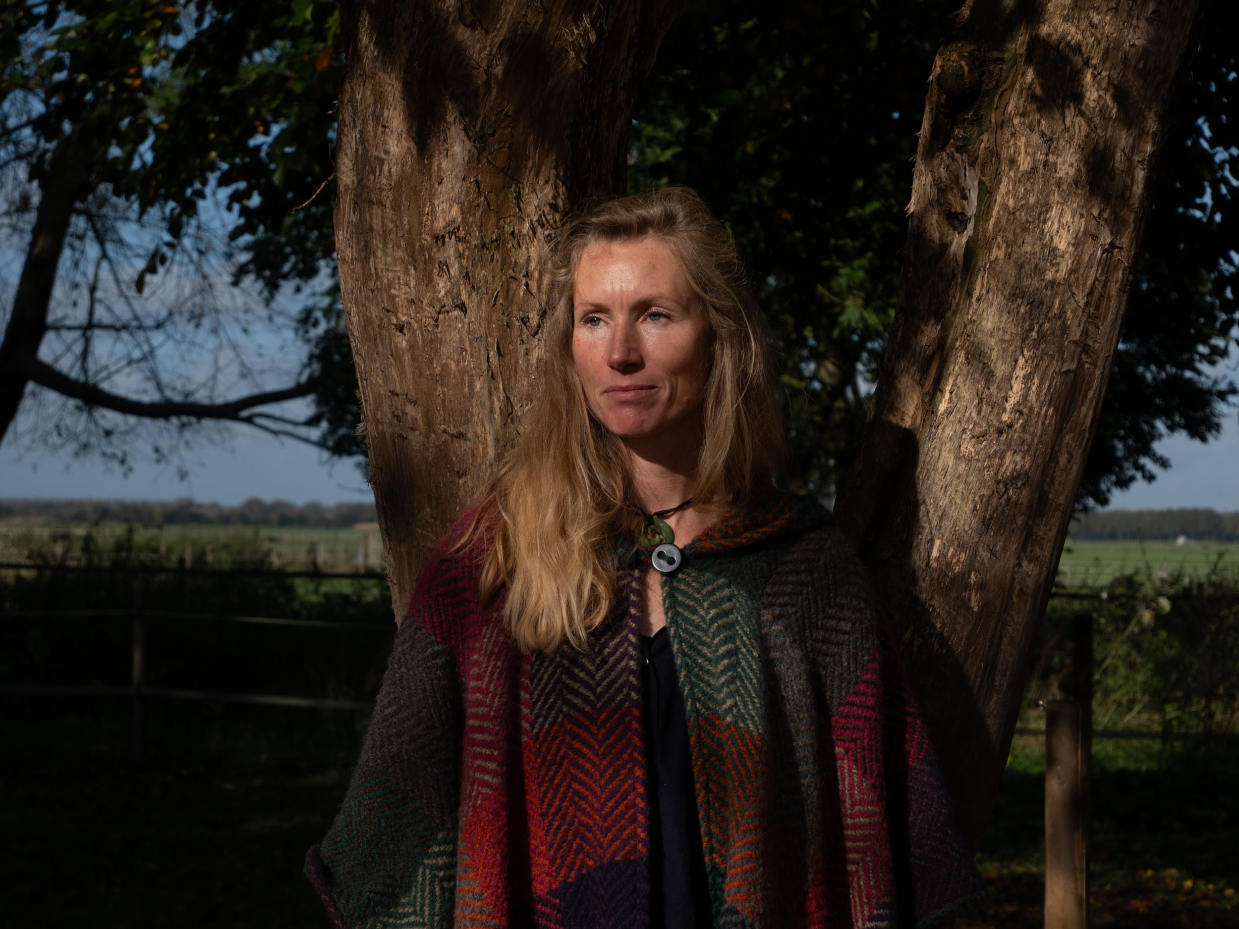 Eva Krom standing beside a tree in a wooded setting